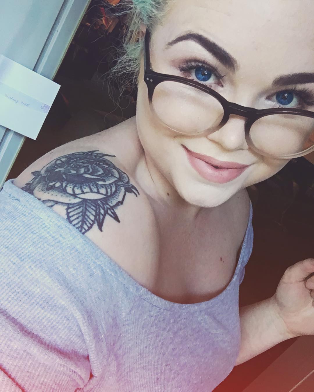Girl with glasses shows off her rose shoulder tattoo